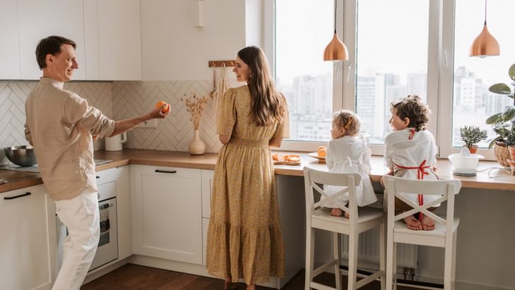 A family having fun preparing breakfast in a cozy kitchen with a city view.